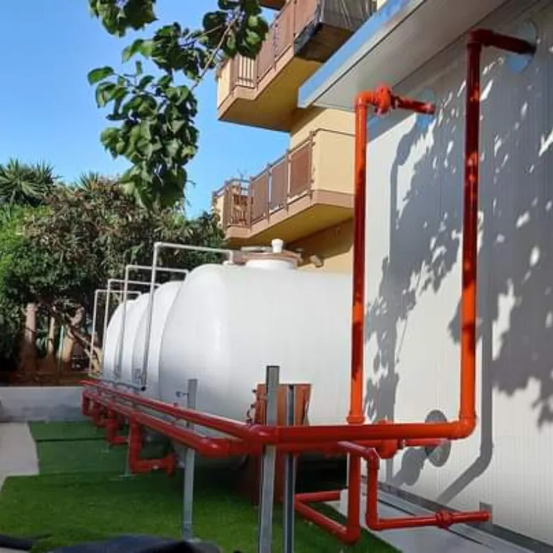 Serbatoi di accumulo con tubazioni antincendio rosse lungo la parete di un edificio