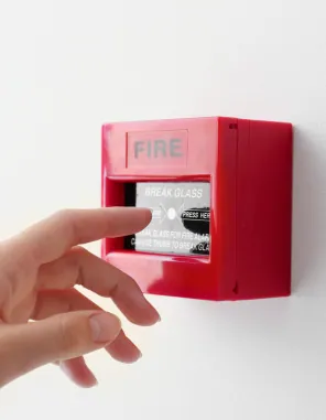 Mano che preme il pulsante manuale di allarme antincendio